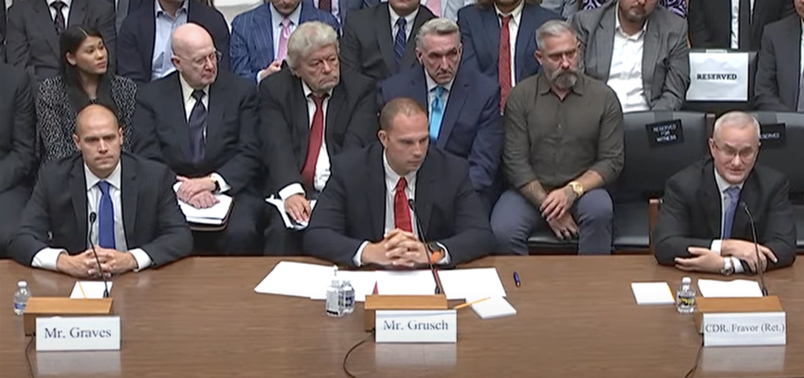 Blick in den Anhörungssaal des US-Repräsentantenhauses am 26. Juli 2023: David Grusch, David Fravor und Ryan Graves am Zeugentisch, dahinter im Publikum George Knapp und Jeremy Corbell